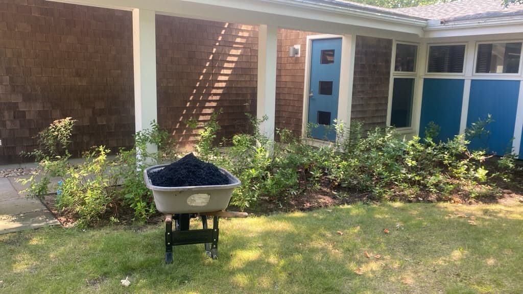 Wheelbarrow of fresh mulch staged in front of a home